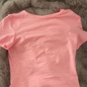 Ljusrosa t-shirt i bomull - Säljer en enkel och fräsch ljusrosa t-shirt med korta ärmar. T-shirten har en klassisk rund hals och är gjord i mjuk bomull, perfekt för en chill och avslappnad stil. Passar dig som gillar basic och färgglada plagg.