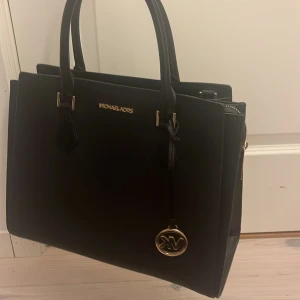 Svart väska från Michael Kors - svart väska från michael kors, använd fåtal gånger och inga skador eller fläckar🫶 nypris runt 3000 kr💗     mått: höjd, 26 cm. bredd, 14 cm.  bredd framifrån, 34 cm💗 köpt i usa och den är äkta.
