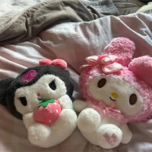 Sanrio  - Bilden visar två mjuka gosedjur från Sanrio, My Melody och Kuromi. De är i fint skick utan synligt slitage och passar perfekt som samlarobjekt eller present till fans av kawaii och japansk popkultur.