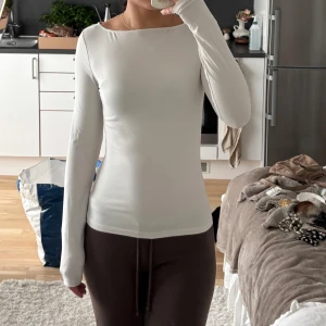 Vit långärmad slim topp - Säljer en stilren vit långärmad topp med smal passform och rundad halsringning. Toppen är enkel och clean i designen, perfekt för dig som gillar minimalistiskt mode. Materialet känns mjukt och stretchigt mot huden, vilket gör den skön att bära hela dagen.
