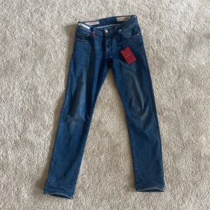 Jeans från Tramarossa - Snygga jeans från Tramarossa Modell: Michelangelo slim Ingår: jeansen, etiketten, bokstäver(UF), avtagbar ring i metall. Storlek: W31 Du kan lätt själv byta initialerna. UF är de som ingår men man kan köpa egna på Tramarossas hemsida. Skriv för fler frågor eller information. Artikeln köpes i befintligt skick.