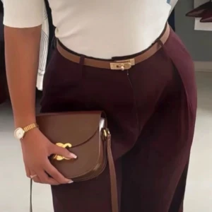 Brunt smalt skärp med guldfärgat spänne - Snyggt och stilrent brunt bälte i skinn med ett unikt guldfärgat låsspänne. Perfekt att bära i midjan eller till byxor för en clean look. Bältet är smalt och har fina sömmar längs kanterna som ger en exklusiv känsla.