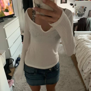 Vit ribbad långärmad tröja - Säljer en vit långärmad tröja med ribbad struktur och v-ringning. Tröjan är figurnära och har en mjuk, stretchig känsla. Perfekt att styla med jeans eller kjol för en clean look.