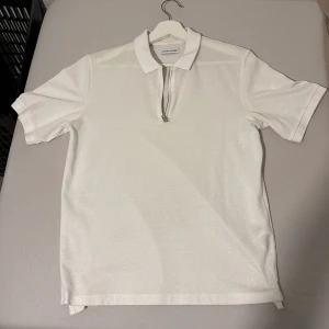 Vit piké med dragkedja Jack & Jones XS - Vit pikétröja från Jack & Jones i storlek XS.  Tillverkad i bomull med lätt struktur i tyget.