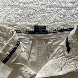 Beige shorts från Morris - Snygga beige shorts från Morris med klassisk passform och stilrena detaljer. Shortsen har knäppning framtill, bälteshällor och fickor både fram och bak. Tillverkade i mjuk bomull som passar perfekt för varma dagar.