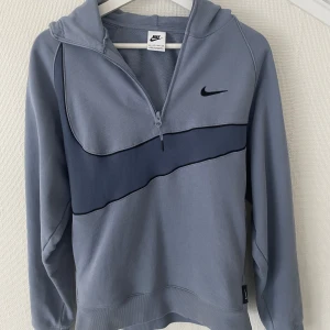Vintage Nike hoodie  - Snygg blå hoodie från Nike med half zip och huva. Tröjan är köpt på Mall Of Scandinavia för ca 1400 kr och har knappt använts. Väldigt unik och har extremt mycket kvar att ge. Pris kan diskuteras vid köp av flera plagg på min profil. Bara att skriva om du undrar något. Svarar snabbt. Står XS men passar upp till minst S. Kan fixa mer noggranna mått vid förfrågan. 