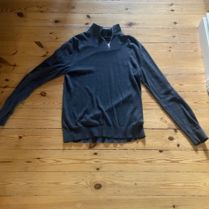 Mörkgrå half zip tröja Jack & Jones - Mörkgrå långärmad tröja från Jack & Jones med half zip-dragkedja i halsen. Tröjan har en klassisk passform och är tillverkad i mjukt material som passar perfekt till kyligare dagar. Enkel och stilren design utan mönster.