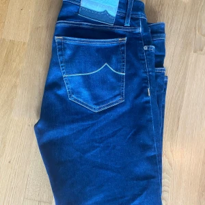 Jacob cohën Jeans  - Snygga blå jeans från Jacob Cohen med klassisk femficksdesign och unika detaljer som broderad text på insidan och patch i ljusblått skinn på linningen. Jeansen har kontrastsömmar och är tillverkade i mjukt denimtyg som sitter skönt hela dagen.