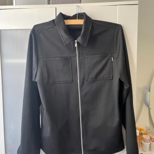 Jack & Jones premium overshirt  - Jätte fin overshirt / skjortjacka Från Jack & Jones premium avdelning Storlek M, liten i storleken Hel svart färg med en silvrig dragkedja Skicka meddelande vid några funderingar Kolla gärna även in mina andra annonser