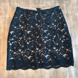 Mörkblå spetskjol från H&M - Supersnygg mörkblå kortkjol från H&M med blommig spets och nude-färgat foder, kjolen har en rak passform och stängs med dragkedja bak💓