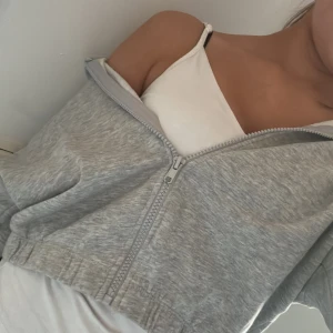 Grå croppad hoodie från 157 New - Grå croppad hoodie från 157 New med dragkedja framtill. Tröjan har en avslappnad passform och är tillverkad i mjuk bomullsblandning.