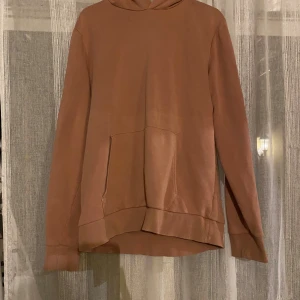 Korall hoodie i ekologisk bomull - Säljer en korall hoodie från C i ekologisk bomull. Tröjan har huva, känguruficka och långa ärmar. Perfekt för dig som gillar en enkel och stilren look. Passformen är normal och materialet är mjukt och skönt.