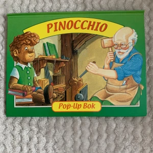 Pinocchio Pop-Up Bok - En färgglad pop-up bok om Pinocchio, den klassiska trädockan som drömmer om att bli en riktig pojke. Perfekt för unga läsare som gillar äventyr och interaktiva böcker med spännande illustrationer och överraskande pop-up-effekter.