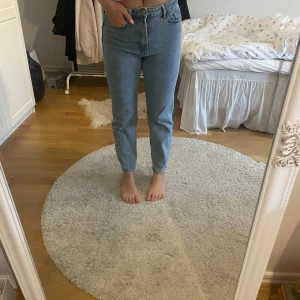 Ljusblå high waist jeans straight fit - Säljer ett par ljusblå jeans med hög midja och raka ben. Klassisk femficksmodell med dragkedja och knapp framtill. Jeansen har en enkel och clean look, perfekta till sneakers eller boots. Materialet är klassisk denim i bomull.