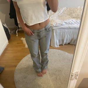 Ljusgrå raka jeans - Säljer ett par ljusgrå jeans med rak passform och klassisk femficksdesign. Jeansen har låg midja och är tillverkade i ett mjukt denimtyg som känns skönt mot huden. Perfekta för en avslappnad och stilren look.