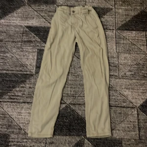 Beige chinos från 157 Grim Star - Snygga beige chinos från 157 Grim Star i storlek 150. Byxorna har raka ben, klassisk passform och elastisk midja baktill för extra komfort. Perfekta för en clean och stilren look. Tillverkade i mjukt bomullstyg med fickor både fram och bak.