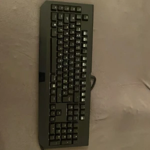 Gamingtangentbord RAZER BLACKWIDOM CHROMA - Svart gamingtangentbord med kabelanslutning. Fullstort med numerisk del och tydliga tangenter. Tangenterna har både latinska och arabiska tecken. Tangentbordet ser ut att vara i gott skick utan synliga skador eller slitage. 