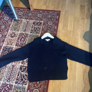 Mörkblå stickad tröja från Gina Tricot - Mörkblå stickad tröja från Gina Tricot med krage och v-ringning. Tröjan har långa ärmar och bred ribbad mudd nedtill för en snygg passform. Perfekt för kyligare dagar och enkel att matcha med jeans eller kjol. Förlåt om bilderna är dåliga min kamera är 💩!