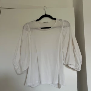 Vit blus med puffärmar från Wera - Säljer en vit blus från Wera med riktigt snygga puffärmar och rund halsringning. Blusen är i ett lätt och mjukt material.