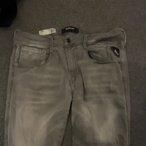 Replay jeans - Snygga Replay Anbass jeans i grå tvätt med klassisk femficksdesign och diskreta slitningar. Jeansen har raka ben och normal passform, tillverkade i mjukt jeanstyg som sitter skönt hela dagen. Perfekta för dig som gillar stilrena och moderna jeans.