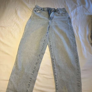 Ljusblå raka jeans från Levi's 501 - Klassiska ljusblå Levi's 501 jeans med rak passform och femficksdesign. Jeansen har normal midja och är tillverkade i slitstarkt denim. Perfekta för en avslappnad och tidlös stil. AI genererad inte säker på varumärket.