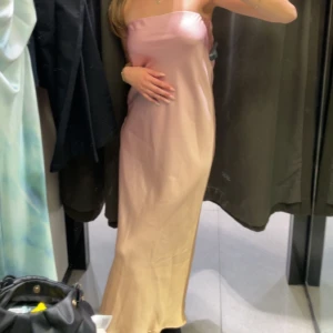 Ljusrosa bandeau långklänning - Säljer en jättefin festlig klänning i satinliknande material. Endast använd en gång 2023 som gäst på ett bröllop🩷