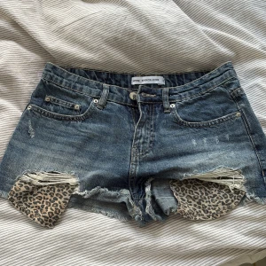Jeansshorts med leopard Sinsay - Snygga blå jeansshorts från Sinsay, fickorna har coola leopardmönstrade detaljer som syns genom de slitna partierna. Perfekta för en trendig sommarlook. Midjemått: 37cm, grenlängd: 26cm