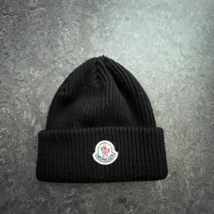 Svart moncler mössa - Svart ribbstickad mössa från Moncler. Använd 2-3 gånger.