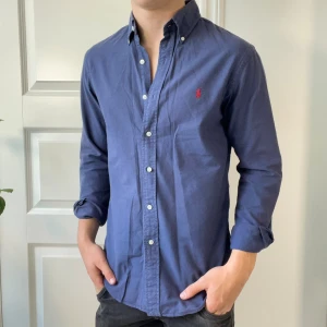 Ralph Lauren skjorta mörkblå S - Ralph Lauren skjorta mörkblå S slim fit, inga defekter. Modellen är 180,75 kg. Kom med frågor 😊 den är använd men inga defekter 