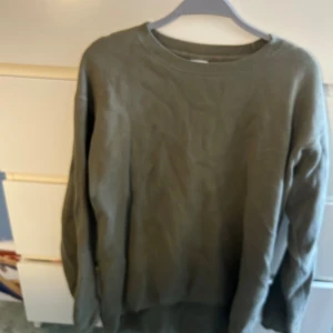 Grön tröja - Olivgrön stickad tröja från Won Hundred med rund halsringning och långa ärmar. Tröjan har en enkel och clean design med ribbade muddar vid hals, ärmslut och nederkant. Perfekt för lager-på-lager under kyliga dagar.