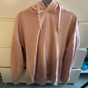Ljusrosa hoodie med snörning - Mysig ljusrosa hoodie i storlek M med huva och snörning. Tröjan har en relaxed passform och är tillverkad i mjukt material, perfekt för chill dagar. Långa ärmar och breda muddar vid ärmslut och nederkant.
