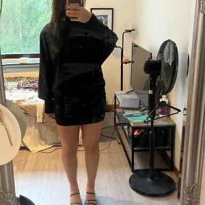 Svart kort pösig klänning - Svart kort pösig klänning med långa ärmar och en öppning i ryggen. Endast använd vit ett tillfälle och är tjock i materialet. 