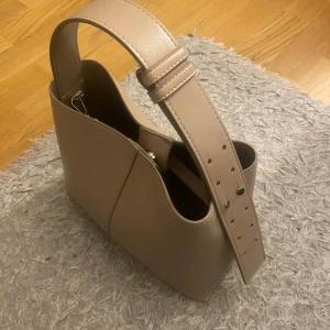 Beige axelväska i skinn med bred rem - Fin väska från mango i nyskick. Det långa bandet går att ta av om man vill.