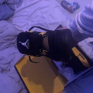 Nike Air Jordan 4 thunder  - Säljer ett par Nike Air Jordan 4 Retro i färgen svart och gul, även känd som 'Tour Yellow' eller 'Lightning'. Skorna har meshpaneler, snörning och den klassiska Jumpman-loggan på plösen och hälen. Kommer i originalkartong. Perfekt för dig som vill sticka ut med en ikonisk sneaker.Äkta, säljer för att skorna inte passar längre perfekt skick 