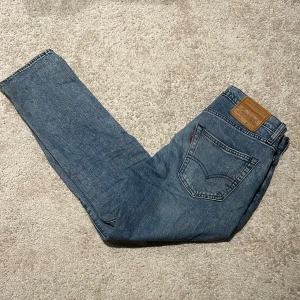 Levi's 502 blå jeans W29 L30 - Klassiska blå Levi's 502 jeans med rak passform och normal midja. Jeansen har fyra fickor och den ikoniska läderpatchen bak. Tillverkade i slitstarkt jeansmaterial, perfekta för en avslappnad och stilren look. De är lite slitna nertill, se bild 5. 