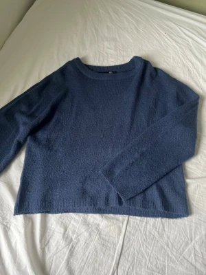 Mörkblå stickad tröja från 157 - Mysig mörkblå stickad tröja från 157 med rund halsringning och långa ärmar. Tröjan har en enkel, clean look och ribbade kanter vid hals, ärmslut och nederkant. Perfekt för lager på lager under kyliga dagar.