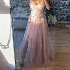 Balklänning  -  Säljer mina kära balklänning från nian, tar studenten nästa år och måste tjäna in pengar, väldigt synd då denna klänning är otroligt vacker och min dröm klänning! Köptes på JJ house. Beskrivning: Superfin ljusrosa långklänning med tunna axelband och v-ringning. Uppe delen är dekorerat med spets och broderade detaljer, medan kjolen är i flera lager tunn tyll med en slits framtill. Perfekt för bal och bara använd en kväll, därav som ny! Kom privat för mått. Passar nog 165-175 beroende på klack