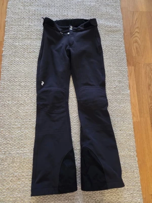 Skidbyxor Peak Performence  - Säljer ett par svarta skidbyxor, softshell med fleecefoder. Tight och väldigt snygg modell. Passar även XS då den har kardborre som går att dra åt i midjan.  Blivit lite slitna nertill pga de varit lite långa för mig (158 cm) se bild och lite ruggade/noppriga baktill (och lite upptill se bild) men annars är de i bra skick och har väldigt mycket mer att ge! 