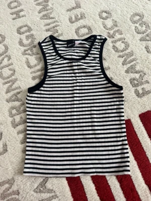 Randig ribbad linnetopp Gina Tricot - Säljer en svartvit ribbad linnetopp från Gina Tricot i storlek S. Toppen har smala axelband, rund halsringning och ett klassiskt randigt mönster. Perfekt till sommaren och enkel att matcha med jeans eller kjol.