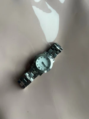 Marc by Marc Jacobs klocka i silver - Klockan fungerar tyvärr inte men den är fin och stilig. Man kan ha den till outfits och man kan säkert laga den.Enda anledningen jag säljer är för jag för guld tjej annars passar deb perfekt och är fin!🥰❤️