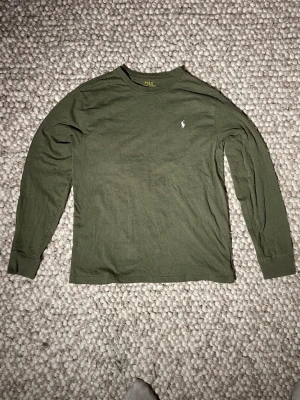 Olivgrön långärmad tröja Polo Ralph Lauren - Snygg olivgrön långärmad tröja från Polo ralph lauren. Tillverkad i mjuk bomull och har en enkel, stilren design. Mycket bra skick. Bara att hör av sig vid funderingar