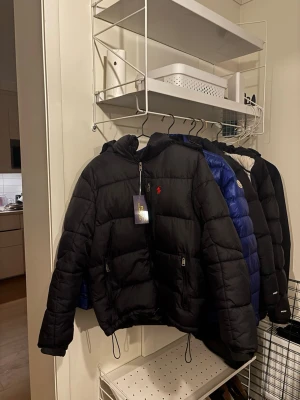 Svart pufferjacka från Polo Ralph Lauren - Hej. Säljer en helt ny ralph lauren vinter jacka som är väldigt eftertraktad. Den är aldrig använd och har därmed inga defekter. Hör av er vid intresse!