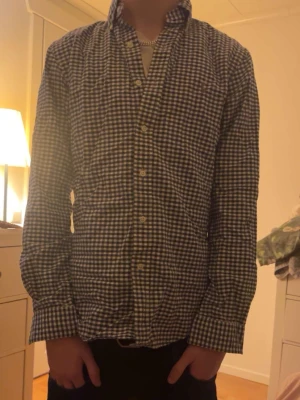 Blårutig skjorta med knappar från Ralph Lauren - Säljer en klassisk blårutig skjorta med vita och mörkblå rutor. Skjortan har lång ärm, knappar hela vägen framtill och en normal passform. Perfekt till jeans eller chinos för en clean look.