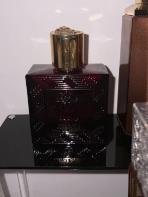 Byte - Versace Eros Flame Eau de Parfum i en elegant röd flaska med guldlock. Perfekt för dig som vill sticka ut med en ikonisk doft från ett välkänt modehus.