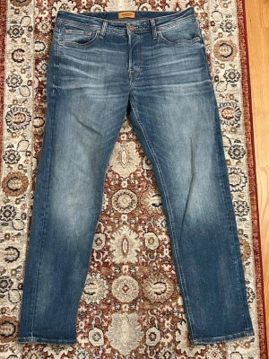 Jack & Jones jeans  - Hej, säljer nu mina extremt fina jeans från märket Jack & Jones i tapered passform. Jeansen är i storlek 34/32 och är fint sick. Modellen på bilden är 188 cm lång och väger 83 kg.