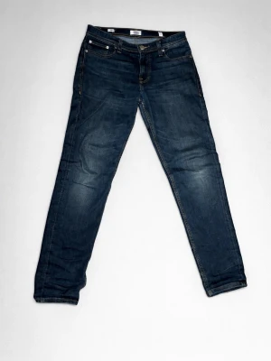 Mörkblå jeans från Jack & Jones - Säljer ett par mörkblå jeans från Jack & Jones med klassisk femficksdesign och snygga kontrastsömmar. Jeansen har normal passform och raka ben, tillverkade i slitstarkt denimtyg. Perfekta till sneakers och hoodie för en chill look.