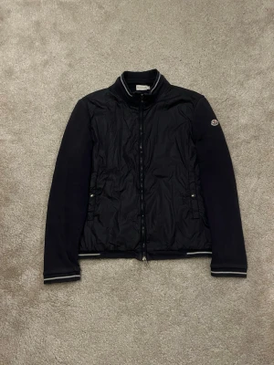 Moncler cardigan Navy - Hej! Säljer denna sällsynta Moncler Maglia Cardigan i färgen Navy! Storleken är XL men sitter bäst på dig som bär M då denna är liten i storleken, (kan skicka bild vid begäran)! Cardiganen är äkta! (Se bild på industries lappen samt loggan). Gott skick och nästan flawless förutom en pytteliten flaw längst ner till vänster på jackan. Skriv vid minsta intresse vid köp! Mvh