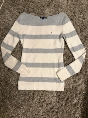 Randig tröja Tommy Hilfiger XS - Säljer en snygg långärmad tröja från Tommy Hilfiger i storlek XS. Tröjan är vit med breda ljusgrå ränder och har en liten logga broderad på bröstet. Tillverkad i mjuk bomull och har en klassisk, normal passform.pris kan diskuteras💕
