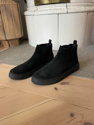 Svarta chelsea boots i mocka - Säljer ett par svarta chelsea boots i mocka stl 42, märke The Original 1936 Copenhagen. Använd vid två tillfällen men dessvärre något för små. 