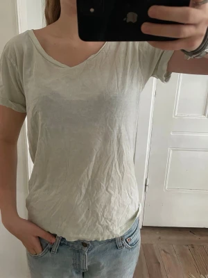 Ljusvit basic t-shirt med v-ringning - Enkel ljusvit t-shirt med v-ringad hals och uppvikta korta ärmar. Skön och luftig passform, perfekt till jeans eller shorts. Tillverkad i mjuk bomull som känns bekväm hela dagen.